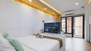 A modern hotel room with a large bed, a flat-screen TV, and a balcony with a view. - Tranquil Studio At Tamansari Semanggi Apartment (Jakarta)