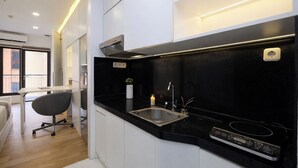 A modern kitchen with a black countertop, stainless steel sink, and a built-in stove. - Tranquil Studio At Tamansari Semanggi Apartment (Jakarta)