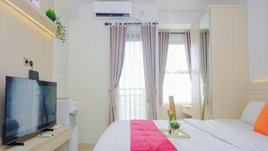 A hotel room with a bed, a TV, a water dispenser, and a window with curtains. - Chic Studio Near Trans Studio Cibubur At Transpark Cibubur Apartment (Depok)