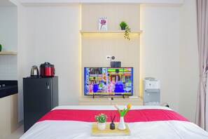 Une chambre d’hôtel équipée d’un lit, d’une télévision, d’un petit coin cuisine et d’un distributeur d’eau.