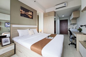 Une chambre d’hôtel comprenant un lit, un bureau, une chaise, une télévision et une armoire.