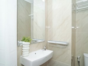 Un baño moderno con un lavabo blanco, un espejo y una zona de ducha.