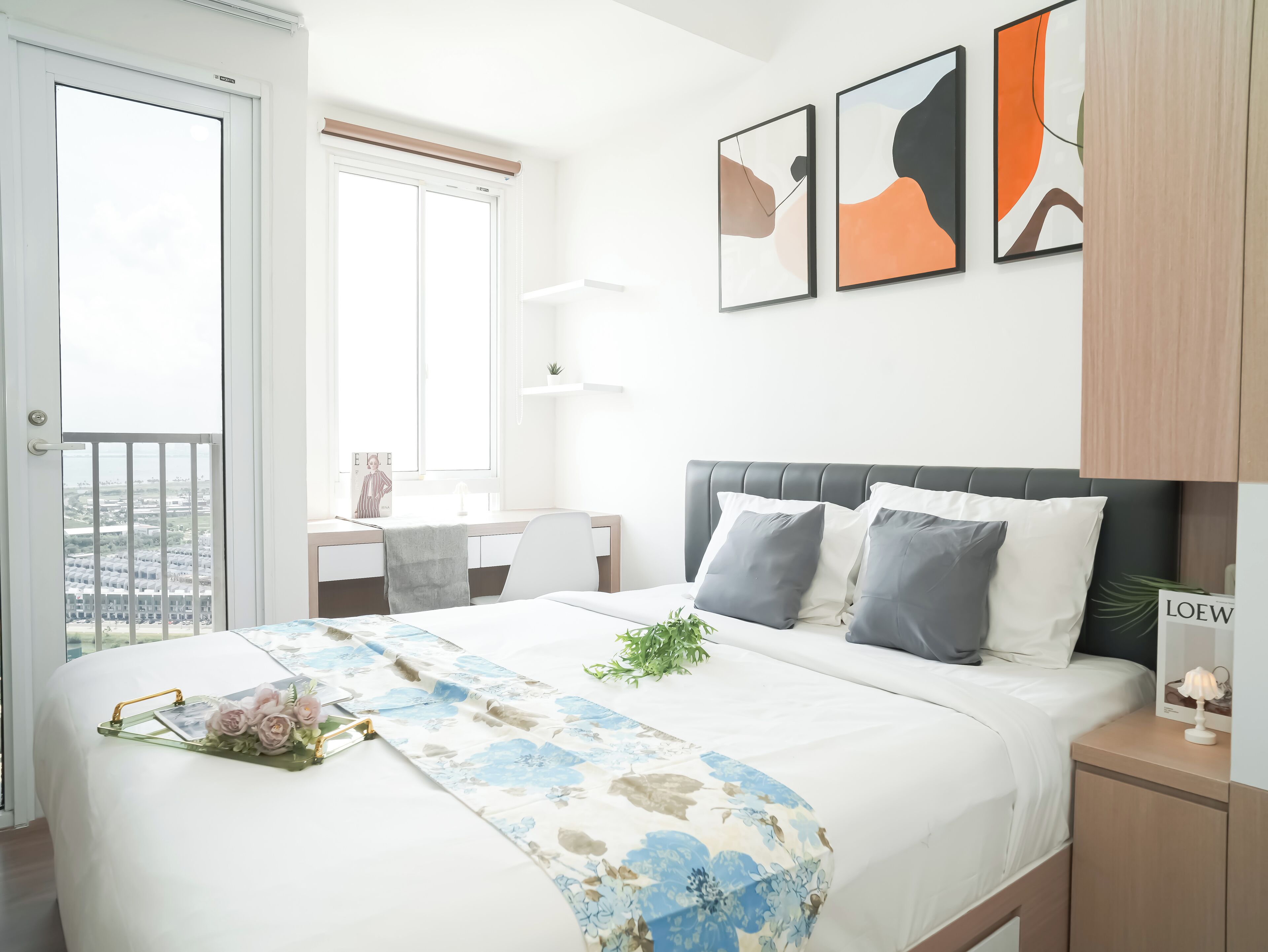 A modern bedroom with a bed, bedside tables, a desk, and a window.