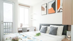 A modern bedroom with a bed, bedside tables, a desk, and a window. - Tranquil Studio For 2 Pax At Tokyo Riverside Pik 2 Apartment (Teluknaga)