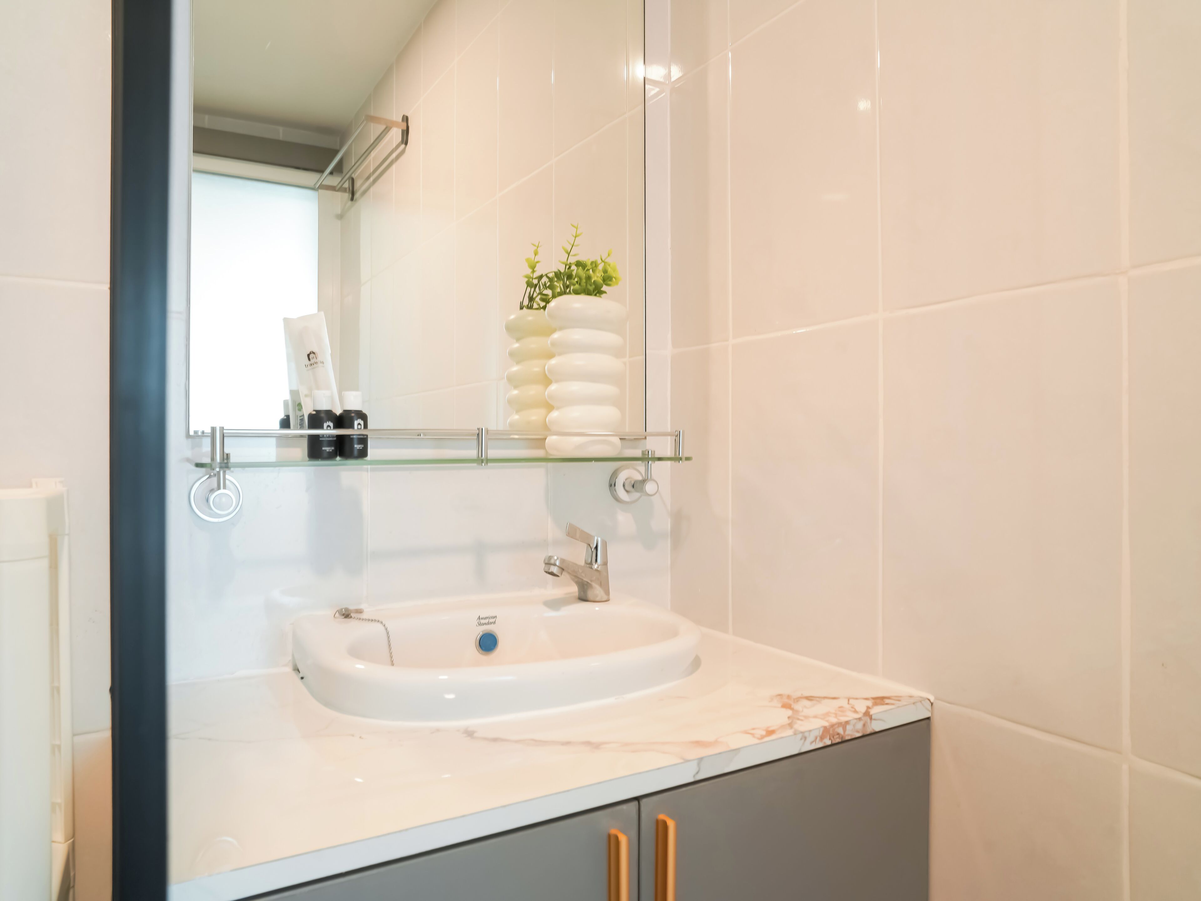 A bathroom with a white sink, a glass shelf above it, and a mirror reflecting the room.