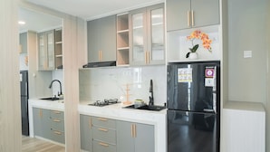 A modern kitchen with grey cabinets, a black refrigerator, and a marble backsplash. - Contemporary And Enjoyable 1Br At Apartment Tokyo Riverside Pik 2 (Teluknaga)