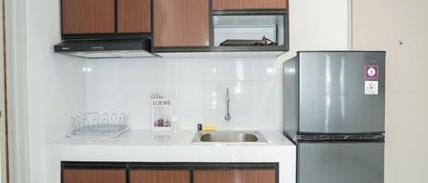 A modern kitchen with wooden cabinets, a stainless steel refrigerator, and a white countertop.