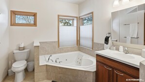 A modern bathroom with a bathtub, toilet, sink, and large mirror. - 2BR 2BA Quiet Coastal Trail Retreat Near Downtown & Medical Centers (Anchorage)