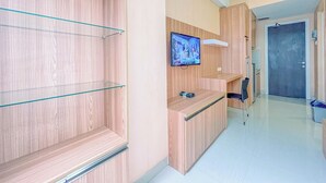 A modern kitchen with wooden cabinets, a built-in TV, and a glass shelf unit. - Great Pure Comfiness Studio At Apartment Student Castle Yogyakarta (Depok)
