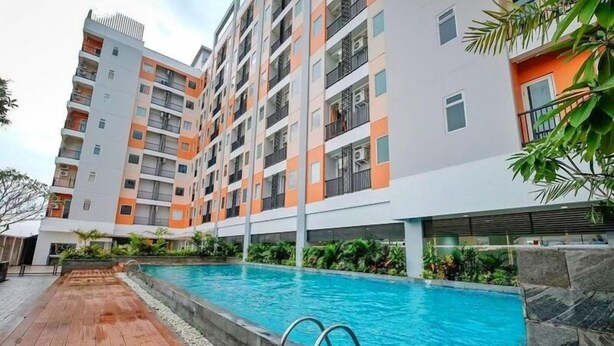 A multi-story residential building with a swimming pool. - Great Pure Comfiness Studio At Apartment Student Castle Yogyakarta (Depok)