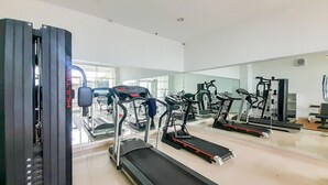 A gym with treadmills, elliptical machines, and weight equipment. - Great Pure Comfiness Studio At Apartment Student Castle Yogyakarta (Depok)
