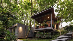 Uma casa moderna com varanda, rodeada por vegetação exuberante e um caminho de pedra.