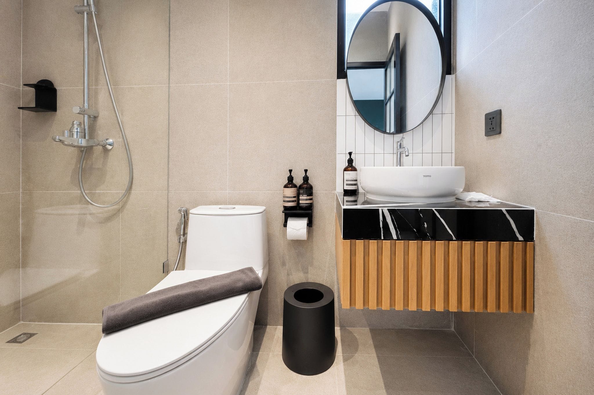 A modern bathroom with a toilet, bidet, sink, and mirror.