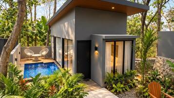 A modern house with a swimming pool, outdoor seating, and lush greenery.