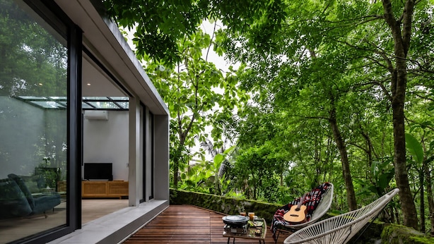 Uma casa moderna com um deck de madeira, uma rede, um violão e uma mesa com uma caixa de som.