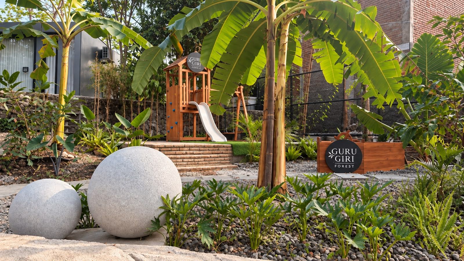 Un parque infantil con un tobogán y una casita de madera, rodeado de grandes esferas de piedra y abundante vegetación.