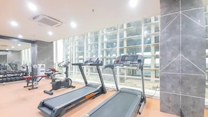 Ein Fitnessstudio mit Laufbändern, Krafttrainingsgeräten und einem großen Fenster.