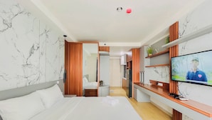 Ein Hotelzimmer mit Bett, Fernseher, Schreibtisch und einem sichtbaren Badezimmer hinter einer geöffneten Tür.