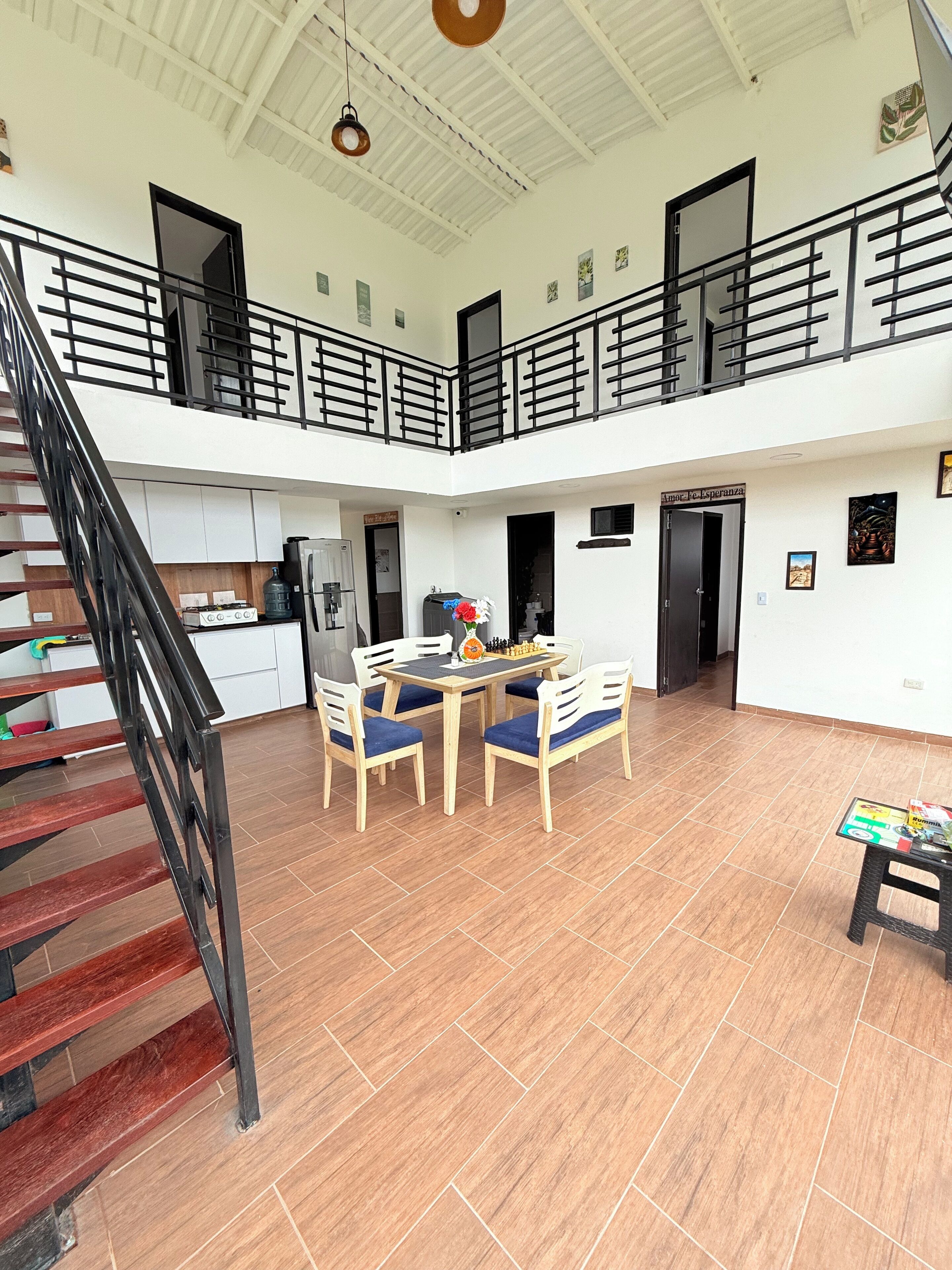 A spacious indoor area with a staircase, a dining table with chairs, and a small table with books.