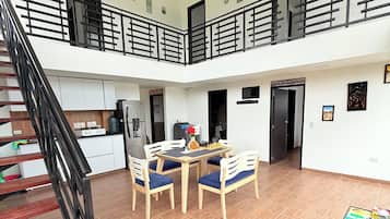 A spacious indoor area with a staircase, a dining table with chairs, and a small table with books.
