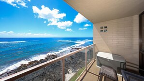 Uma varanda com vista para o oceano, uma parede de tijolos brancos e uma pequena mesa com cadeiras.