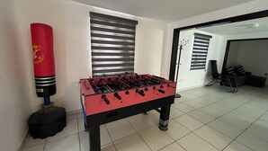 Een kamer met een tafelvoetbaltafel, een bokszak en een kapstok.