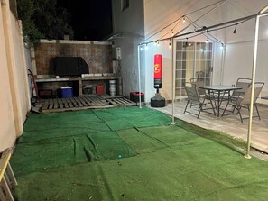 An outdoor patio area with a green artificial turf, a barbecue grill, and a table with chairs. - Tremendous 4-bedroom house with AC in charming Tijuana (Tijuana)