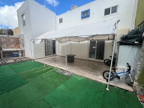A covered patio area with a table and chairs, a motorcycle, and a green artificial turf lawn. - Tremendous 4-bedroom house with AC in charming Tijuana (Tijuana)