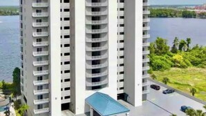 A high-rise building with multiple balconies, a covered entrance, and a view of a lake. -  Sunrise lake view from the balcony. 3-bedroom condo near Disney/universal. (Orlando)