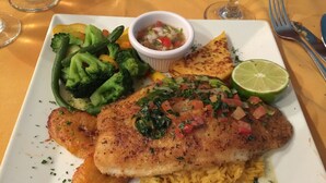 Um prato com um filé de peixe, arroz e legumes.