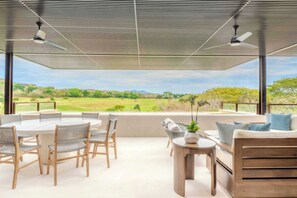 A covered outdoor seating area with a table and chairs, a sofa, and a view of a green landscape. - Condo Tukipa–Lake & Golf Views in Punta Mita (Punta Mita)