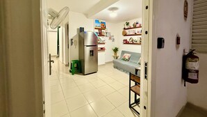 Una cocina con un refrigerador, un ventilador y un taburete verde.