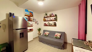 Un espacio habitable compacto con kitchenette, un sofá y una pequeña mesa.