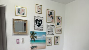 Un dormitorio con una cama, una mesita de noche y una pared decorada con cuadros enmarcados y un espejo.