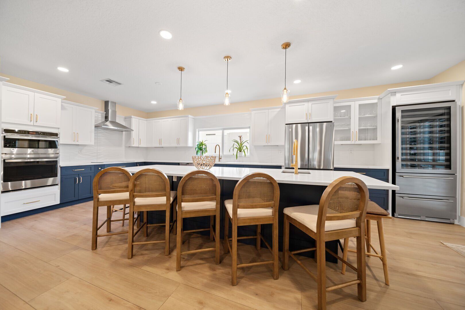 A modern kitchen with white cabinets, stainless steel appliances, and a central island with chairs.