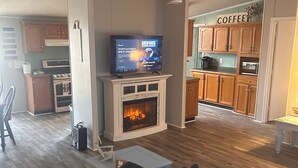 Een woonkamer met een open haard, een televisie en houten vloeren.
