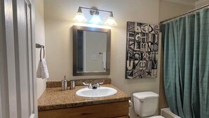 A bathroom with a sink, mirror, toilet, and shower curtain.
