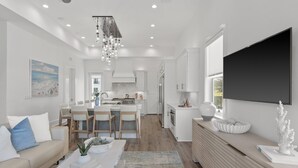 Une cuisine moderne dotée d’un îlot central, d’un coin repas avec des chaises, d’un canapé et d’une table basse.