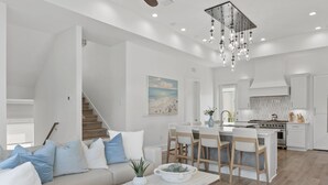 Un salon moderne avec un canapé, une table basse et un coin repas comprenant des chaises, et une cuisine en arrière-plan.