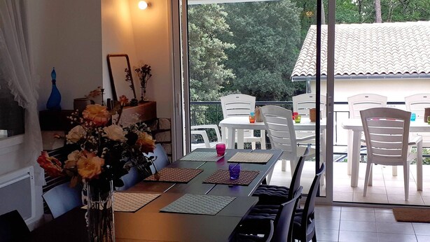 En matplats med ett bord dukat för fyra personer, en vas med blommor och utsikt över omgivningen.