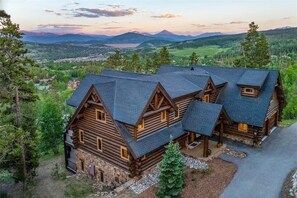 A large log cabin with multiple rooms, surrounded by a mountainous landscape and a lake. - Log Masterpiece with 5 Master Suites, Pool Table, Hot Tub (Silverthorne)