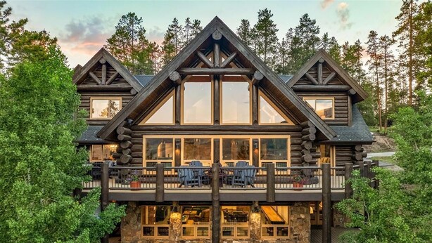 A log cabin with a balcony, large windows, and a stone foundation. - Log Masterpiece with 5 Master Suites, Pool Table, Hot Tub (Silverthorne)