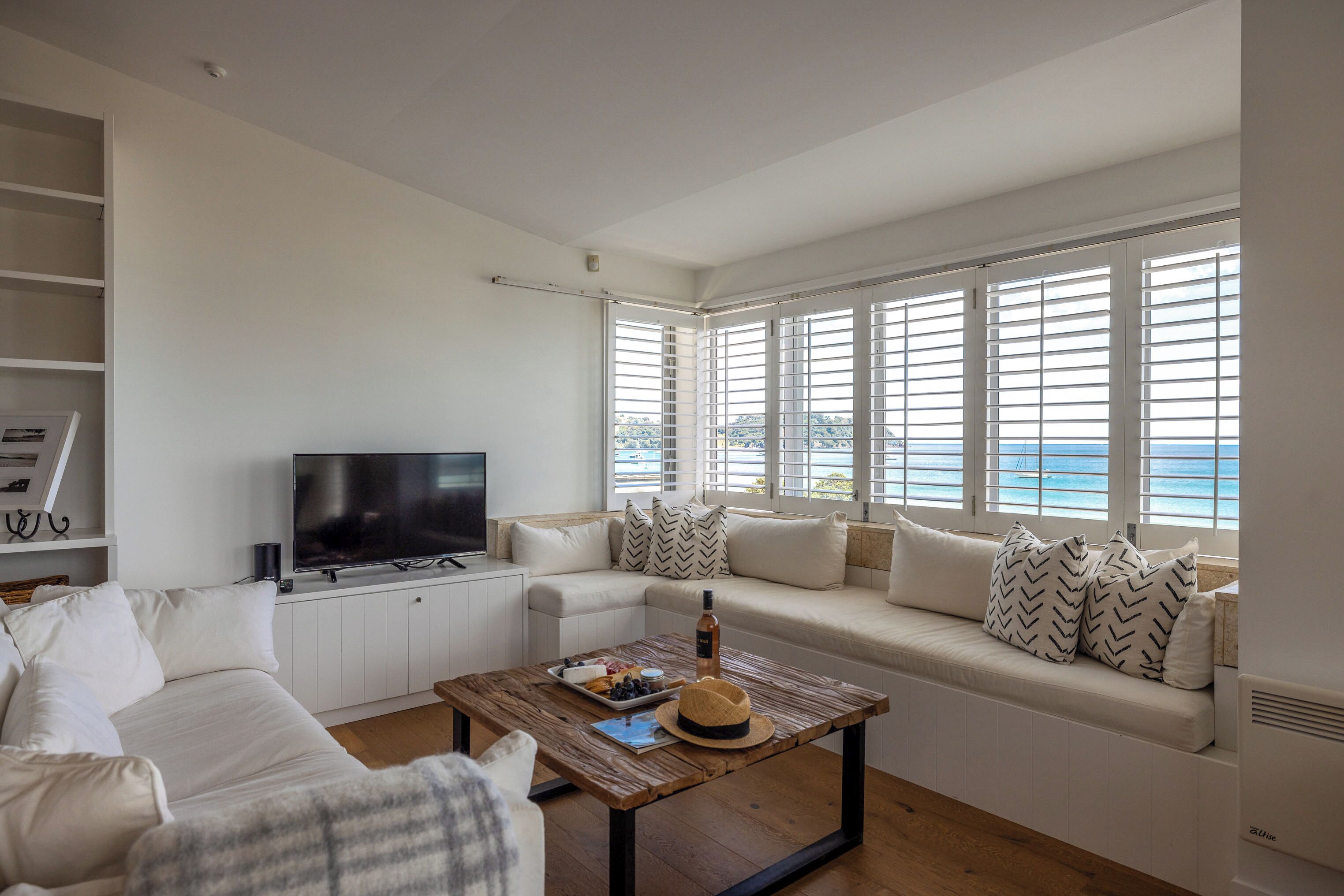 A modern living room with a sofa, television, and a wooden coffee table.