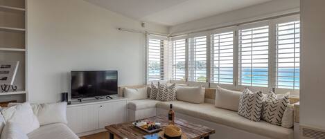 A modern living room with a sofa, television, and a wooden coffee table.