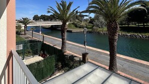 Un balcón con vista a un río, palmeras y un puente.