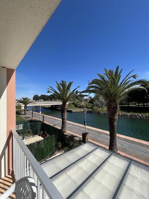 Ein Balkon mit Blick auf einen Fluss, Palmen und eine Brücke.
