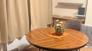 Une table de salle à manger ronde en bois, agrémentée d’un centre de table en forme de panier tressé, une chaise en cuir marron et un tapis moelleux.