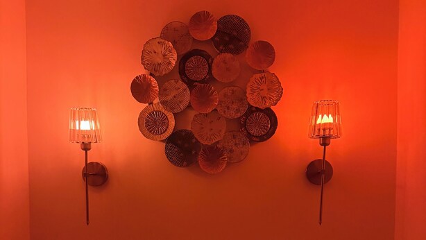Une pièce comprenant un lit, deux lampes fixées au mur et un élément décoratif circulaire sur le mur.