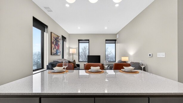 A modern kitchen with a large island, two sofas, a TV, and a dining area with a table set for two. - Across from Clinic | 2 Bed/2 Bath | Free Garage (Cleveland)
