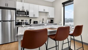 A modern kitchen with stainless steel appliances, white cabinetry, and a dining area with brown chairs. - Across from Clinic | 2 Bed/2 Bath | Free Garage (Cleveland)